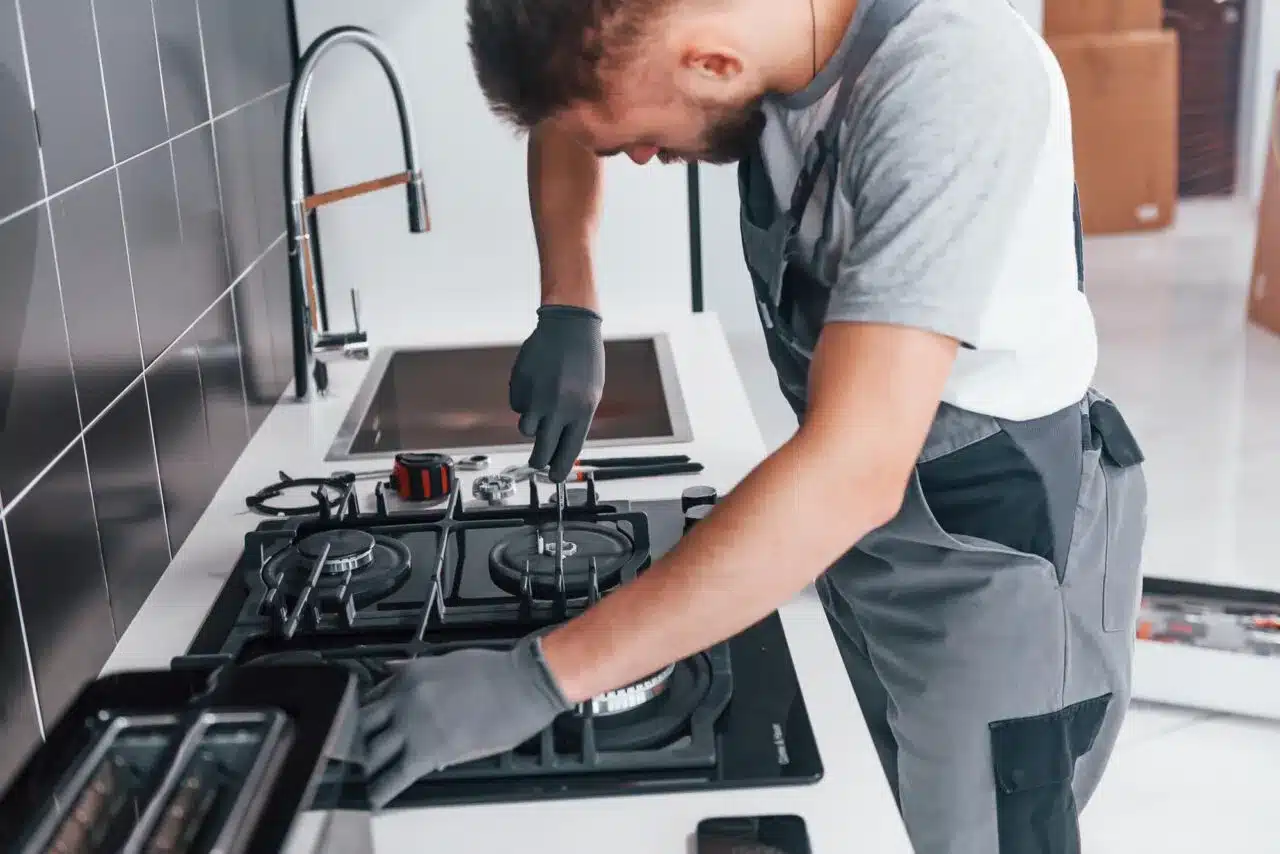 Tecnico specializzato in assistenza per piani cottura  a gas e a induzione in una cucina moderna a Trieste